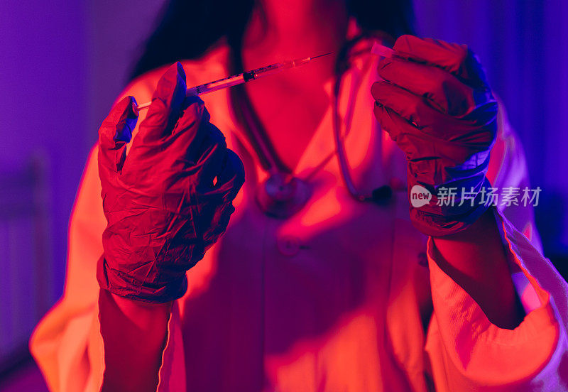 Doctor holding COVID-19, Ñoronavirus vaccine in the syringe using for prevent infection in ultraviolet neon light. Medicine and Healthcare concept.